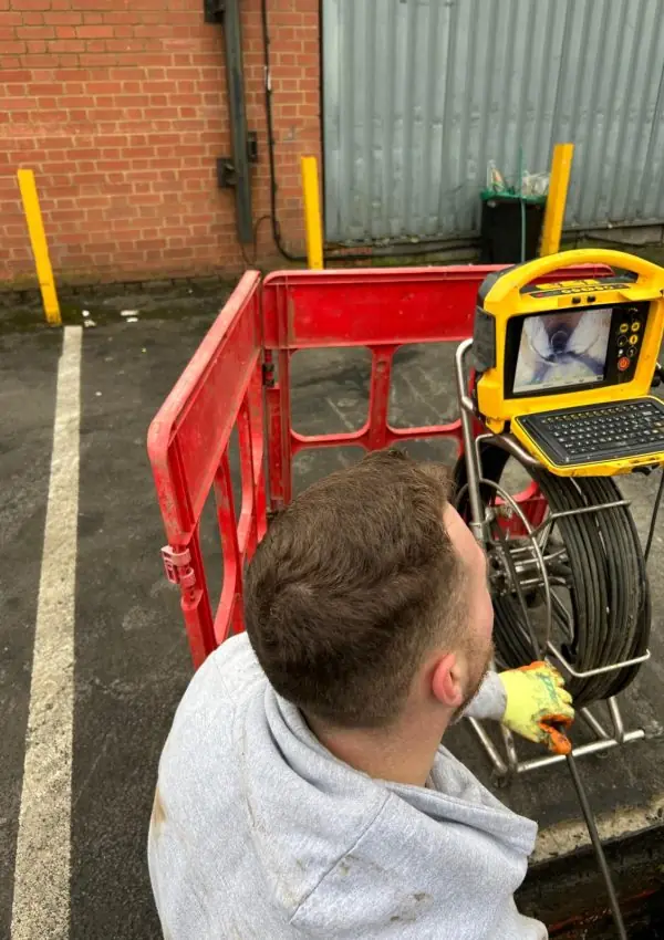 Engineer running a CCTV drain survey at a commercial yard