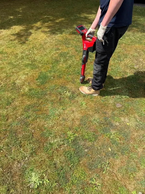 Engineer tracing a drain run across a lawn